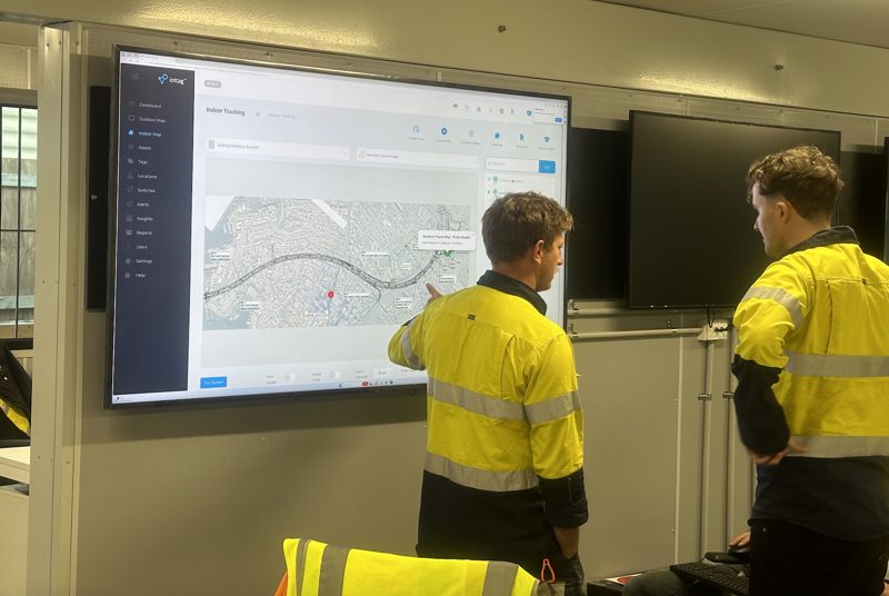 Workers reviewing live tracking dashboards on a wall screen