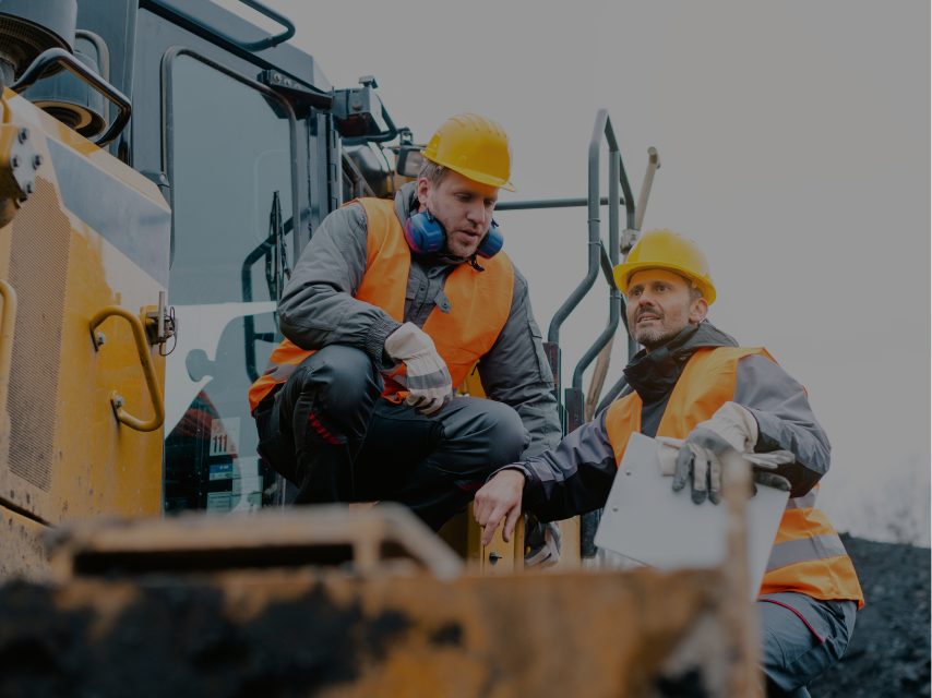 Two workers with hearing protection reviewing equipment on site
