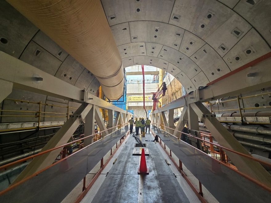 Workers walking through a completed segment-lined rail tunnel