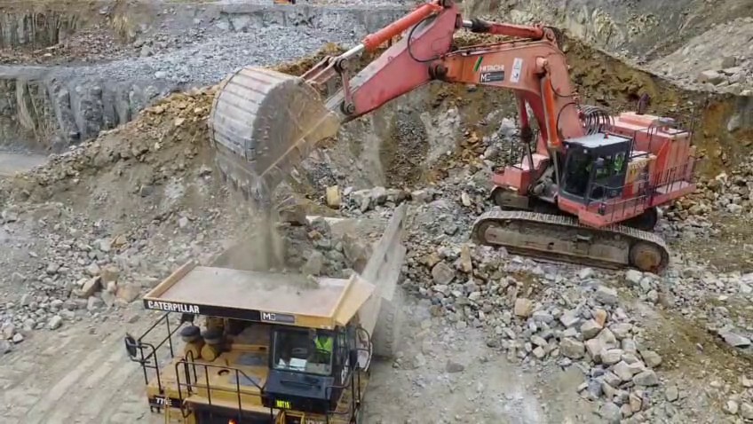 Excavator loading rock into a haul truck on a quarry bench
