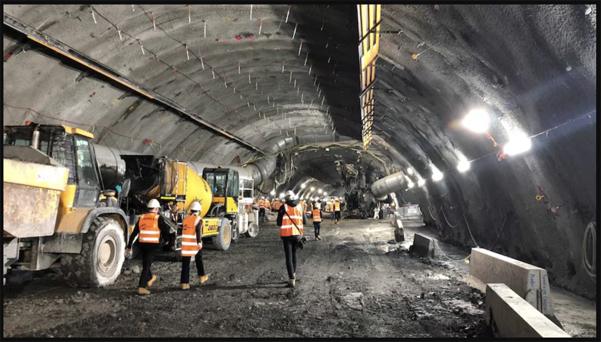 Crew and heavy equipment working beneath an excavated tunnel arch