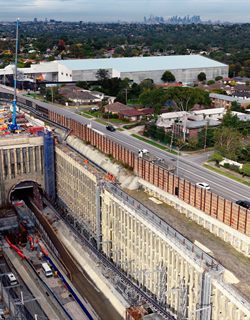 Aerial view of a highway and tunnel portal corridor beside suburban streets